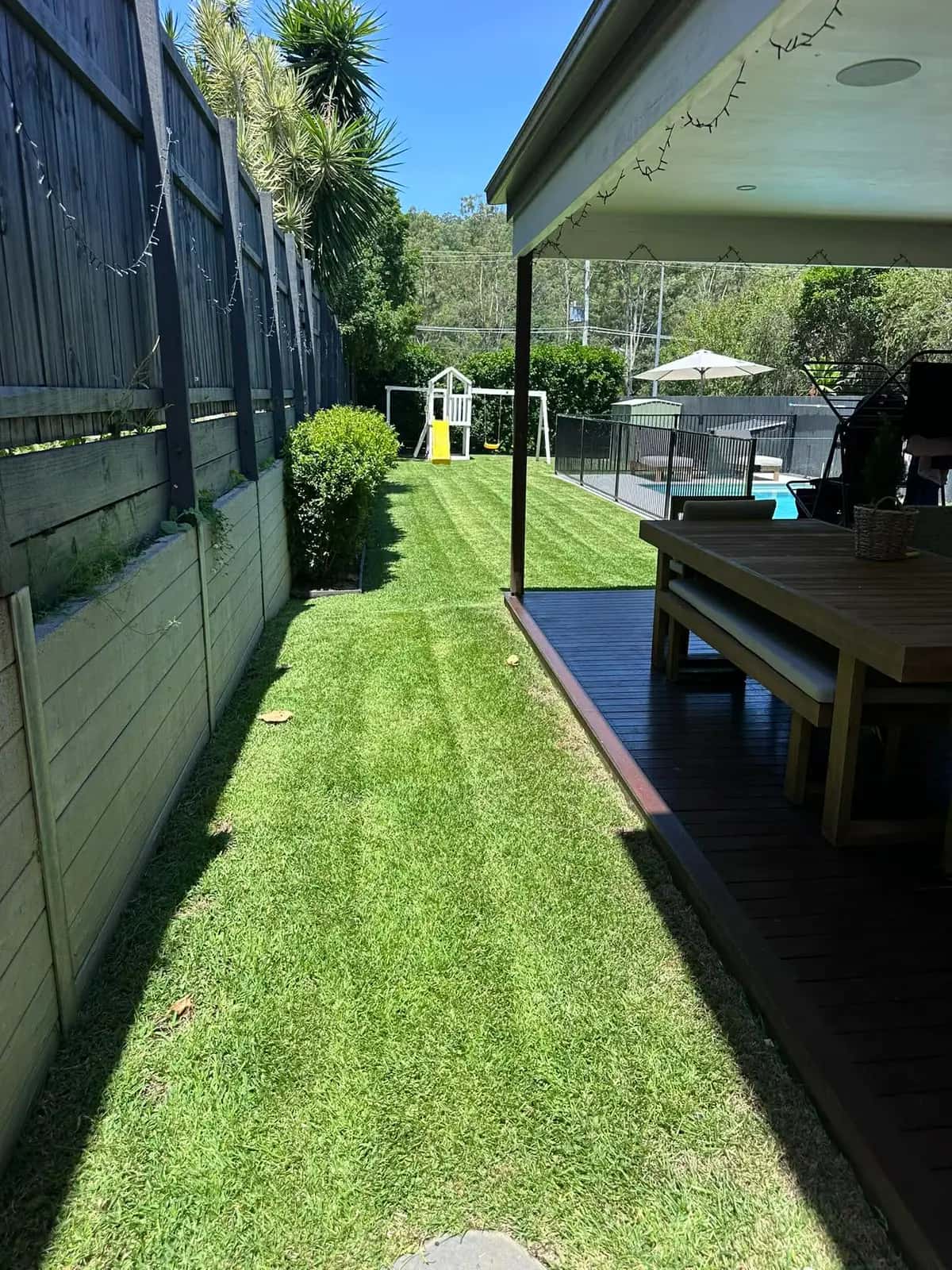 A freshly mowed lawn with crisp edging and a tidy garden bed, maintained by The Yard Gurus
